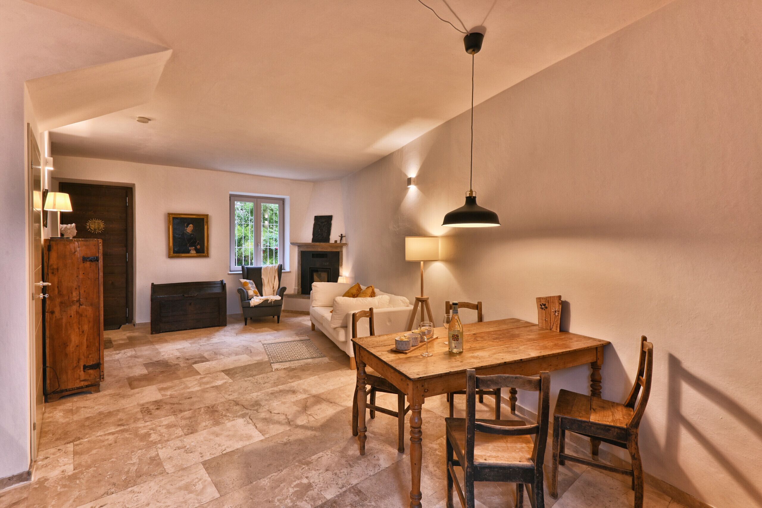 Ein Essbereich mit Holztisch und Stühlen, einer Kandelaberleuchte und einem Kamin im Hintergrund.