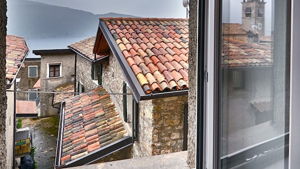 A window with a view of a town's buildings, a church tower, and a body of water.