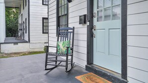 Una casa blanca con una puerta verde y una mecedora en el porche.