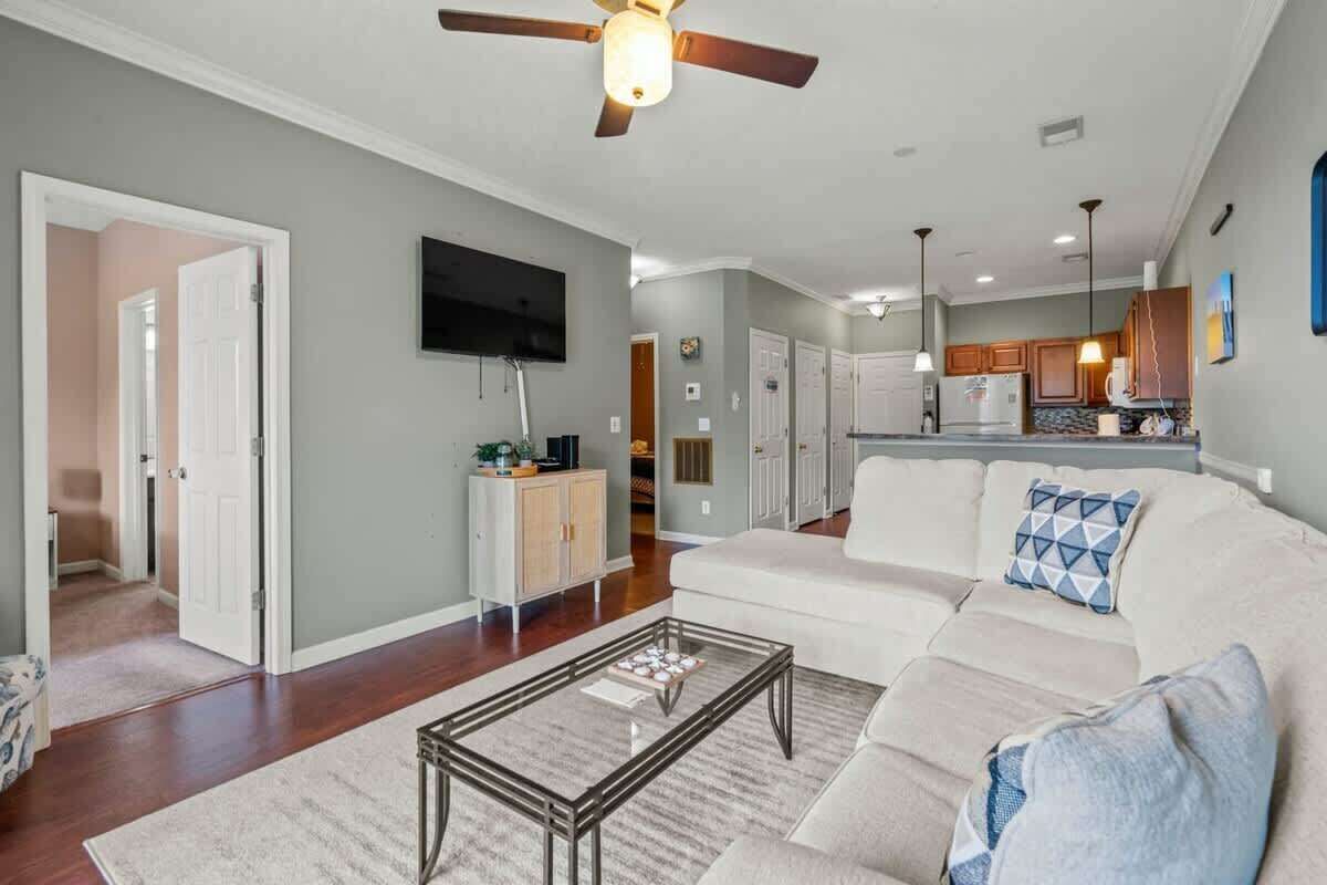 A spacious living room with a large sofa, a coffee table, and a ceiling fan.