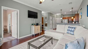 A spacious living room with a large sofa, a coffee table, and a ceiling fan. - River Oaks Unit 63C -Near Golf Areas! (Myrtle Beach)