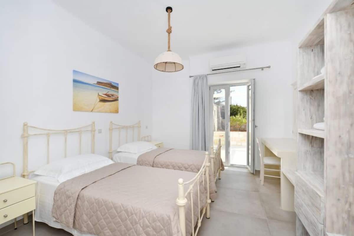 Un dormitorio con dos camas, un escritorio y vistas al exterior.