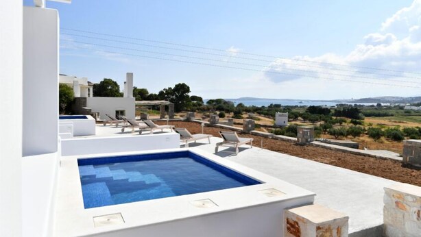 Una piscina en la azotea con sillones de descanso, vistas despejadas del paisaje circundante y un estilo arquitectónico moderno.