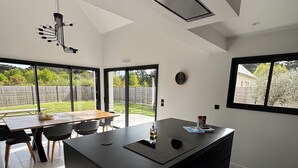 Una cucina moderna con isola centrale, ampie finestre e zona pranzo con tavolo e sedie.