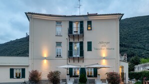 A building with a balcony, outdoor seating, and a sign reading "Albergo alle Vecchie Mura." - Hotel Vecchie Mura  (Finale Ligure)