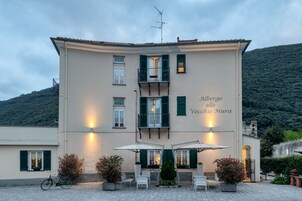 Un edificio con un balcone, un'area salotto esterna e un cartello che riporta la scritta "Albergo alle Vecchie Mura".