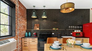 Een moderne keuken met een bakstenen muur, een zwart textuur backsplash en een eethoek met een houten tafel gedekt voor twee personen.