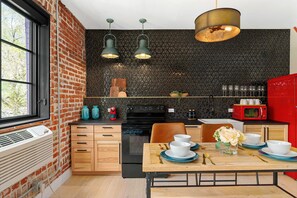 A modern kitchen with a brick wall, black textured backsplash, and wooden cabinets. - Alex Pangburn Suite 212 (Denver)