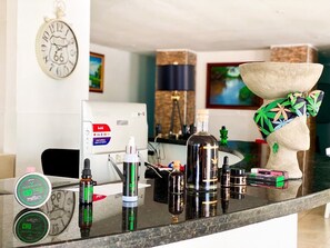 A kitchen counter with various items including CBD products, a bottle, a vape pen, and a decorative head sculpture. - Hotel Zensi 420 (Lejanías)