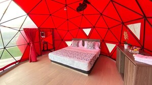 A bedroom with a geometric red ceiling, a bed with patterned bedding, a wooden desk, and a view of the outdoors. - Hotel Zensi 420 (Lejanías)