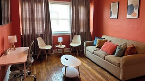 Un salon comprenant un canapé, deux fauteuils, une petite table et une lampe.