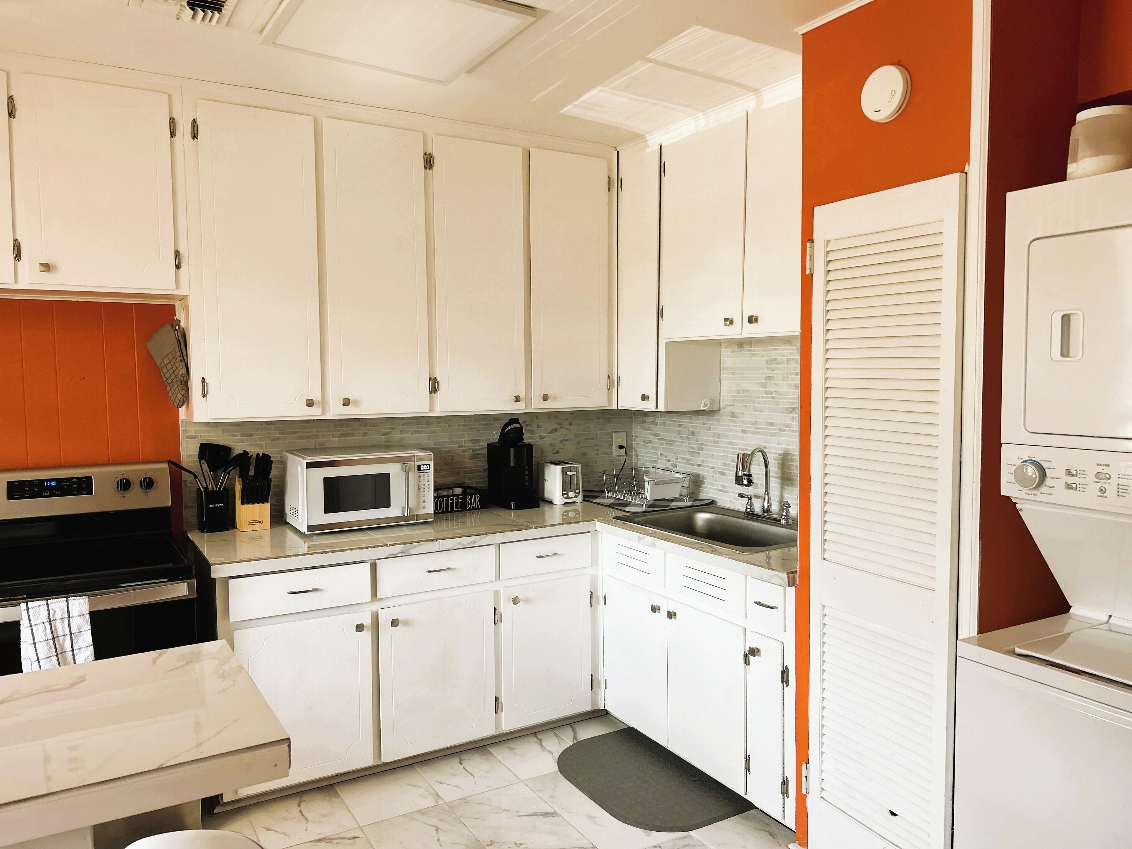 A compact kitchen with white cabinets, a microwave, a coffee maker, and a dishwasher.