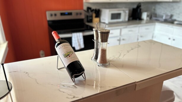 Une cuisine avec un plan de travail en marbre, une bouteille de vin Altosur et un salier.