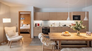 Een moderne keuken met houten kastjes, een eettafel met een fruitschaal, en een pluizige witte hond.