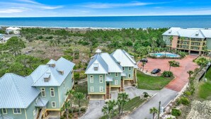 A coastal hotel with multiple buildings, a swimming pool, and a beach view.