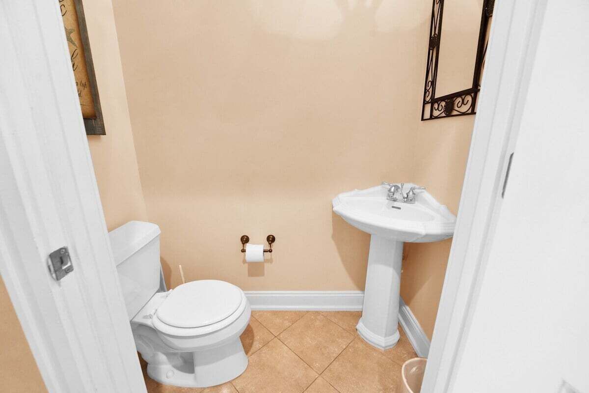 Un baño pequeño con inodoro, lavabo y espejo en la pared.