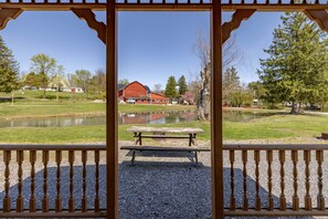 A wooden pergola with a gravel ground, overlooking a pond and a red barn. - Cozy Cabin2 Within Campground (Mifflinburg)