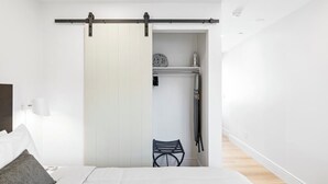 A bedroom with a bed, a nightstand, a lamp, a sliding door leading to a walk-in closet, and a chair.