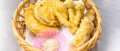 A basket containing fried food items and a pink paper cup with a granular substance, placed on a metallic surface.