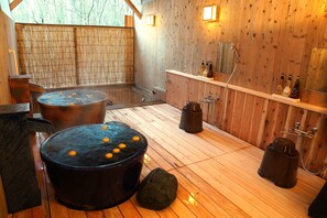A traditional wooden room with a hot spring bath, a stone basin, and a shelf with bottles. - KITAKARUIZAWA Golden Forest Hotel  (Naganohara)