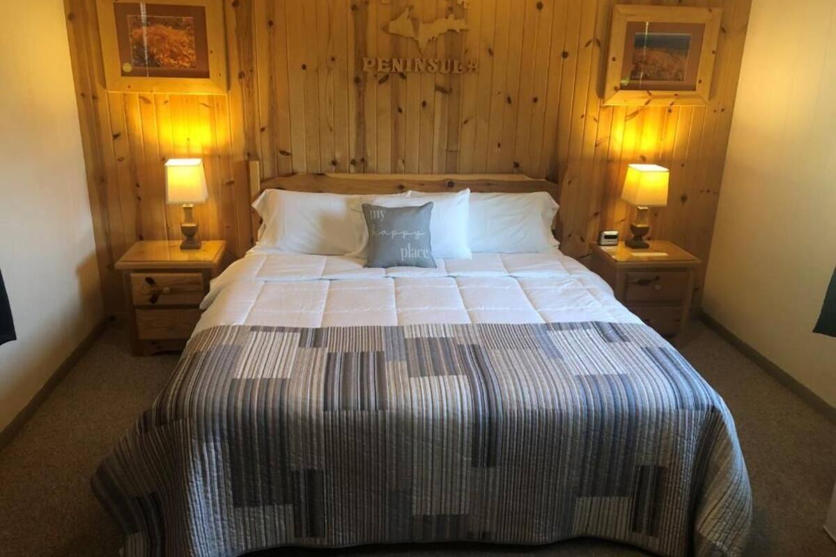 A neatly made bed with a striped bedspread, two bedside lamps, and a framed map on the wall above the bed.