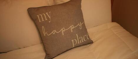 Un cuscino con la scritta "my happy place" su un letto.