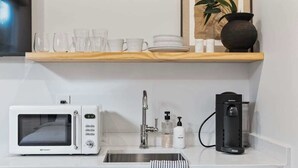 Eine moderne Küche mit weißer Arbeitsplatte, einer Mikrowelle, einer Kaffeemaschine und einem Spülbecken.