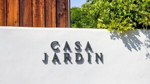 Eine weiße Wand mit der Aufschrift 'CASA JARDIN' in Metallbuchstaben.