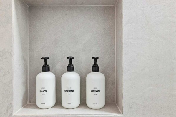 Three white bottles of public goods shampoo, conditioner, and body wash in a white shelf. - Casa Jardin - Studio 3 (Santa Barbara)