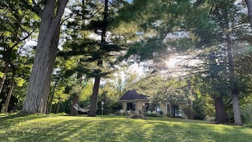 Une maison entourée de grands arbres et d’une pelouse verdoyante.