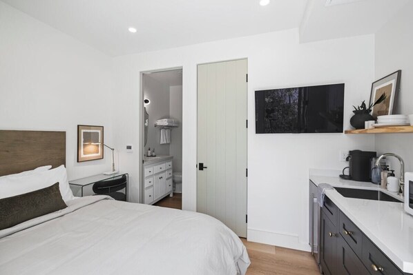Une chambre d’hôtel moderne dotée d’un grand lit, d’un bureau, d’une coiffeuse et d’un coin cuisine.