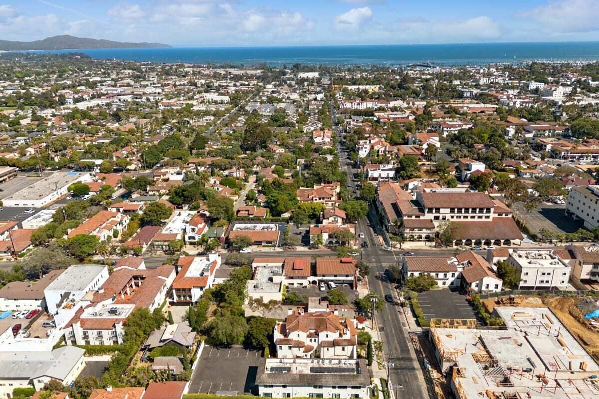 A residential area with houses, streets, and a coastline in the background.
