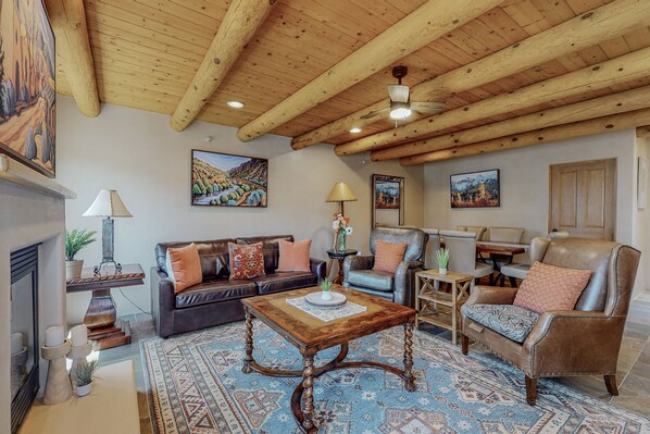 Una sala de estar acogedora con techo de madera, chimenea, sofá, mesa de centro y alfombra.