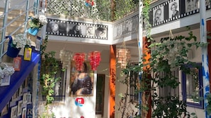 Un atrio de varios niveles con una escalera, plantas decorativas y cuadros en las paredes.