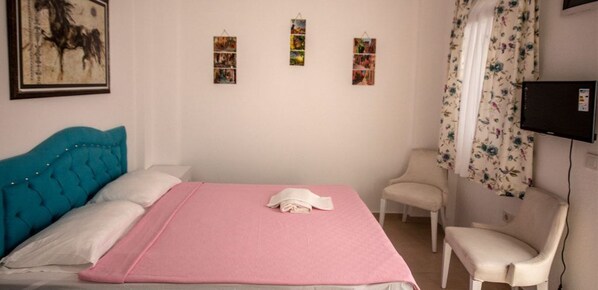 A bedroom with a bed, a chair, and a TV.