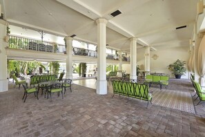 A covered outdoor area with multiple levels, green cushioned seating, and potted plants. - Summer Suite | Steps to Beach + Heated Pool (Palm Beach)
