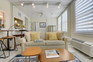 A living room with a sofa, coffee table, and a desk with a lamp.
