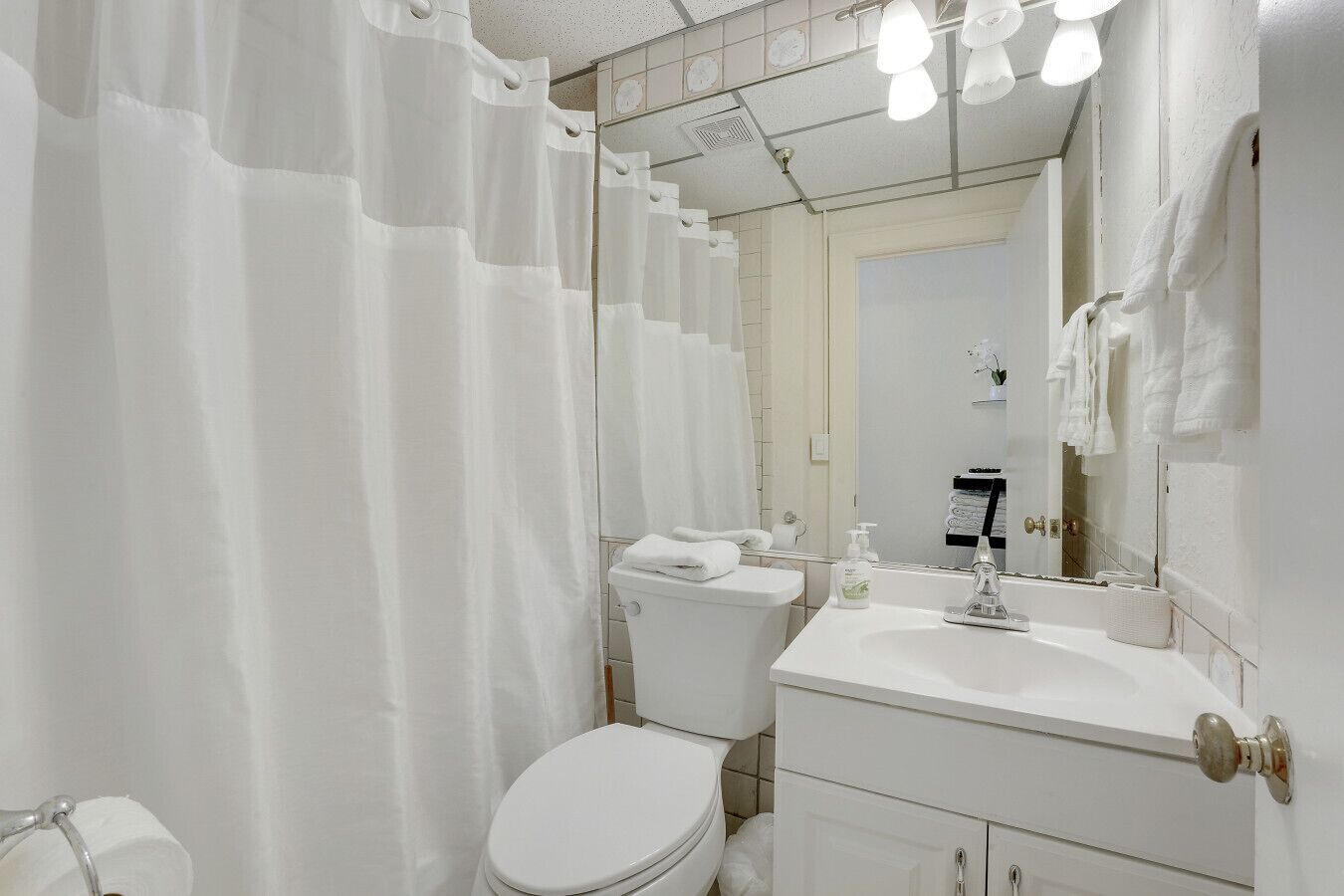 Un baño con inodoro, lavamanos y cortina de ducha.