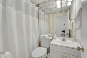 A bathroom with a toilet, sink, and shower curtain.