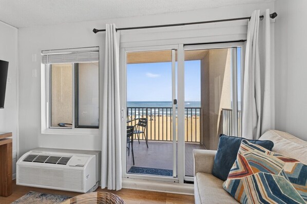 A room with a sliding glass door leading to a balcony with a view of the beach. - Huge Corner Balcony |Sunrise Ocean Views|Pool 407 (Virginia Beach)