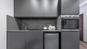 Une cuisine moderne avec des meubles de couleur grise, un four encastré, un lave-vaisselle et une bouilloire.