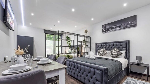Une chambre moderne avec un grand lit, un coin repas et un téléviseur fixé au mur.