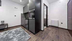 Une cuisine moderne dotée d’appareils électroménagers intégrés, d’un tapis gris et d’un radiateur.