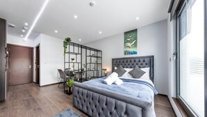 A modern bedroom with a large bed, a desk, and a shelving unit. - Serviced Modern Luxury Flat near Central London (Greater London)