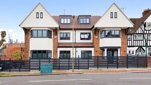 A two-story residential building with a symmetrical facade, large windows, and a black fence in front. - Serviced Modern Luxury Flat near Central London (Greater London)