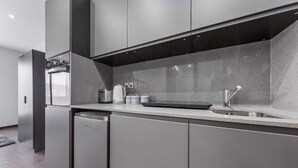 A modern kitchen with stainless steel appliances, a built-in oven, and a sink. - Serviced Modern Luxury Flat near Central London (Greater London)