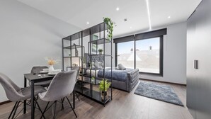 A modern living room with a dining area, a sofa, a coffee table, and a bookshelf. - Serviced Modern Luxury Flat near Central London (Greater London)