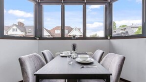 A dining area with a table set for four, large windows, and a view of houses.
