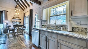 A kitchen with wooden floors, granite countertops, and a large window with a view of trees. - Picture Perfect | $179 Off Your Stay! (Blue Ridge)