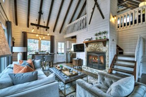 A cozy living room with a fireplace, comfortable seating, and a staircase leading to an upper level.